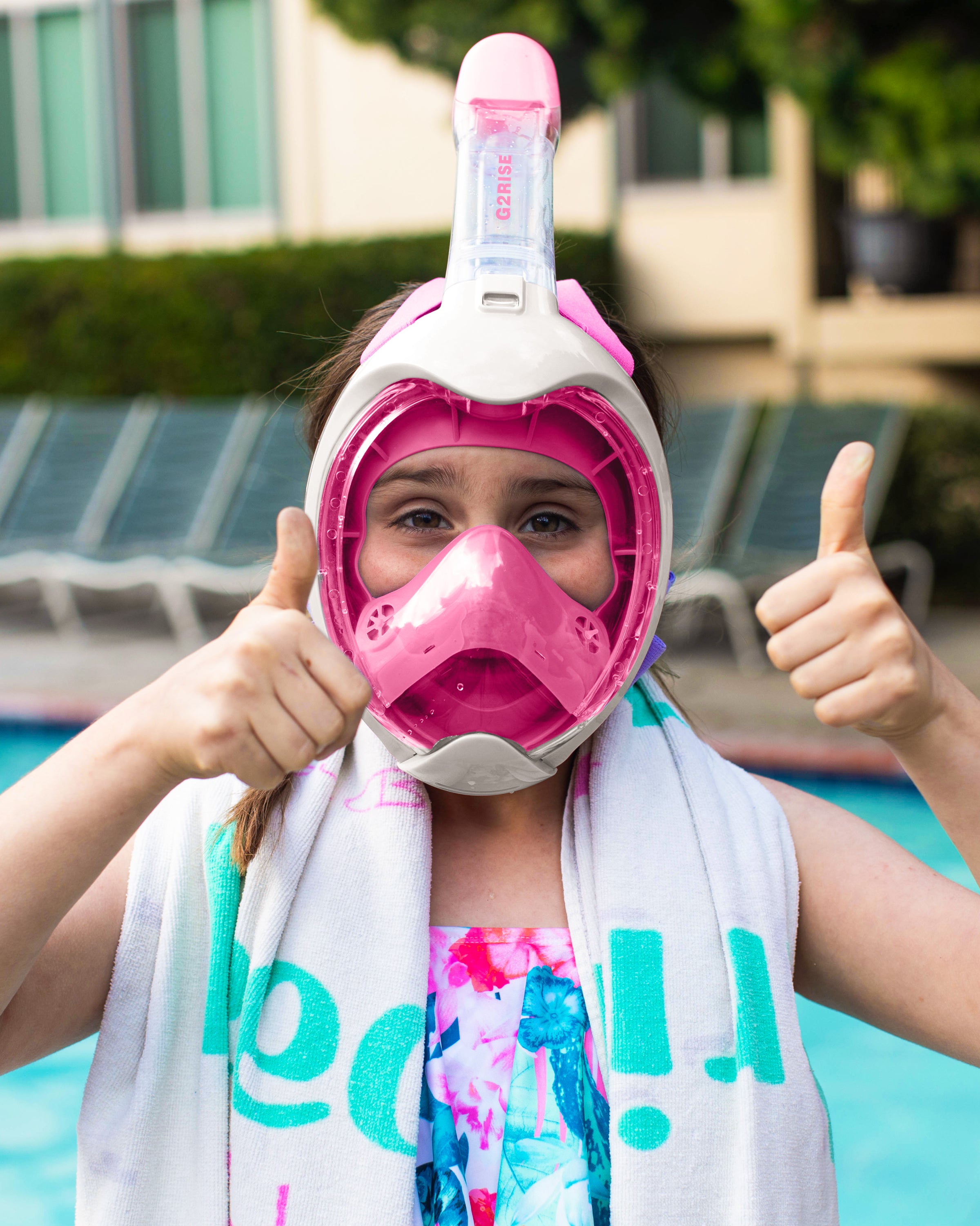 Girl with pink full face snorkel mask giving a thumbs up near swimming pool